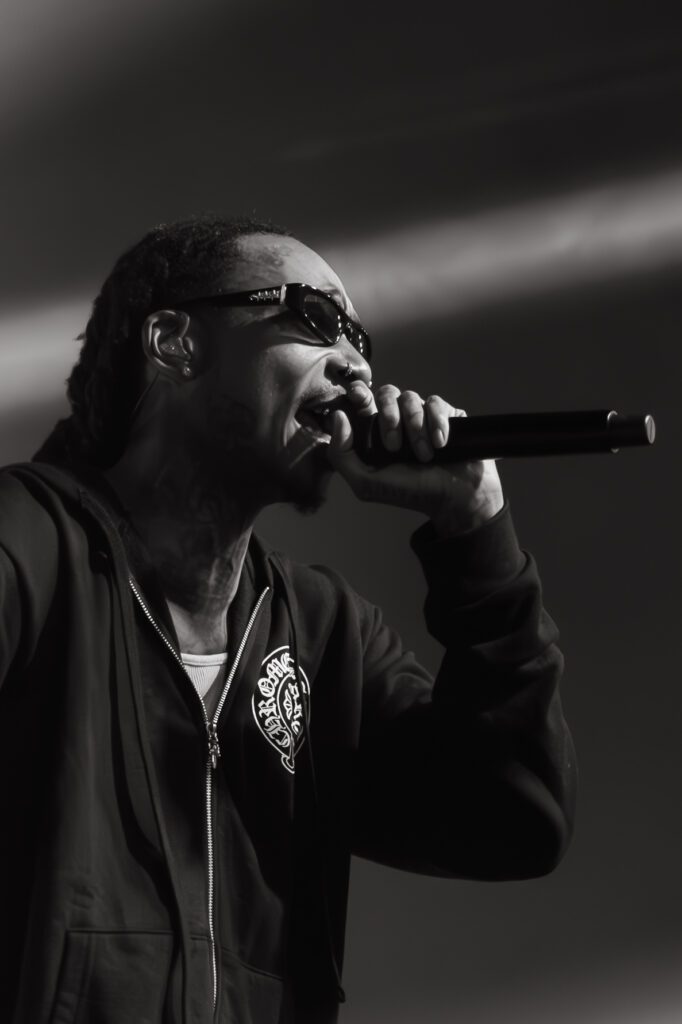 Wiz Khalifa live at The Hall Little Rock rapping into a microphone, wearing sunglasses and a hoodie, black and white image